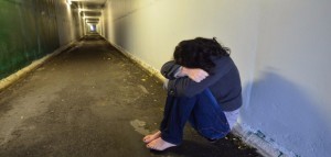 Crime scene simulation of rape victim of a sad woman sits on the floor of a walking tunnel.